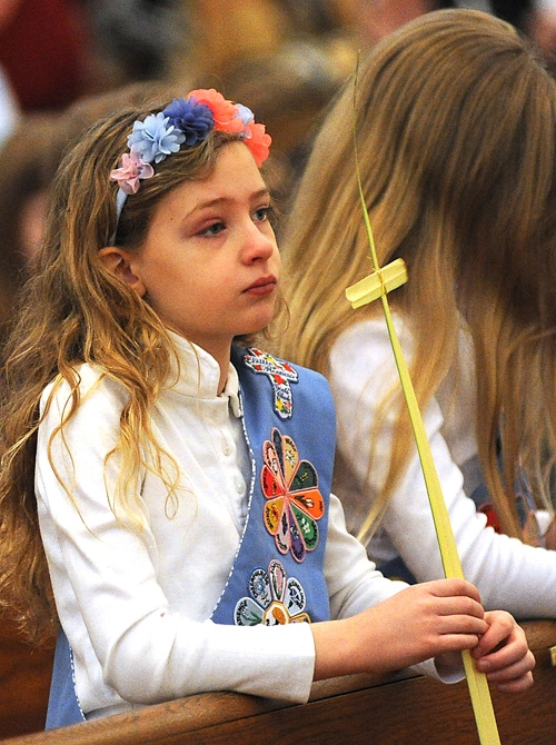 9-year-old Elizabeth Thompson, of Our Lady of Victory Basilica, completes a cross from a blessed palm during Palm Sunday Mass at St Joseph Cathedral. (Dan Cappellazzo/Staff Photographer)